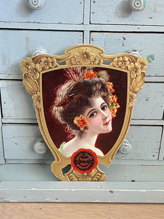 Ancienne réclame en carton découpé et gaufré pour le Nougat Jacob Stuve Zwolle Bruxelles, portrait de femme de style Art Nouveau dans un cadre floral doré.