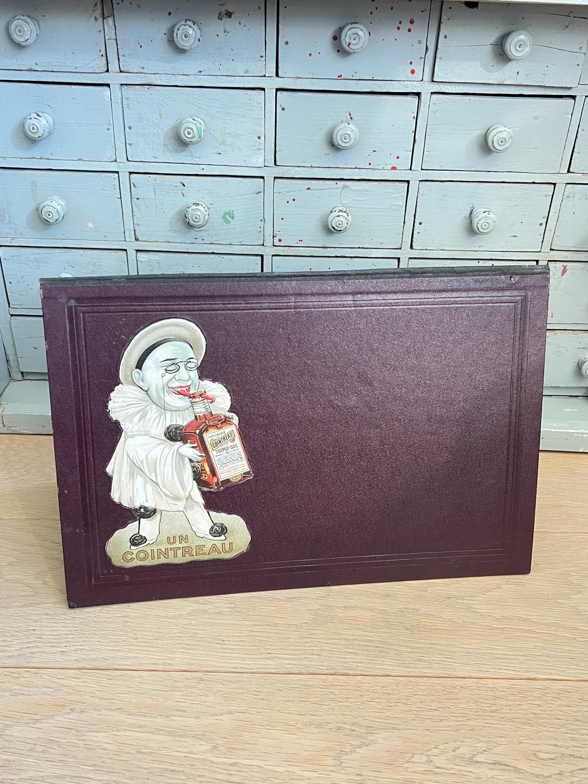Ancien protège-menu de bar publicitaire Cointreau bordeaux en carton gaufré avec illustration de Pierrot de Tamagno en relief et bouteille de triple sec.
