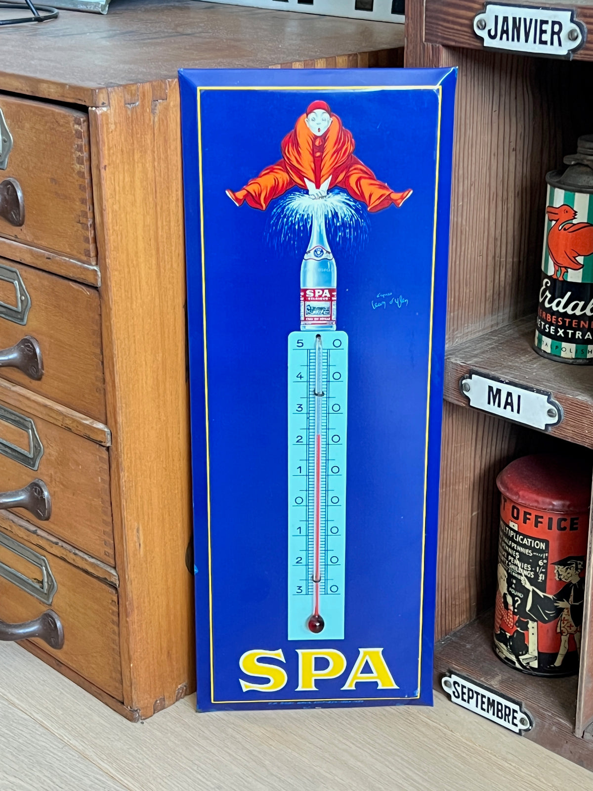 Ancien thermomètre publicitaire vertical en tôle bleue de la marque belge SPA représentant le Pierrot jaillissant d'une bouteille, signé Jean d'Ylen.