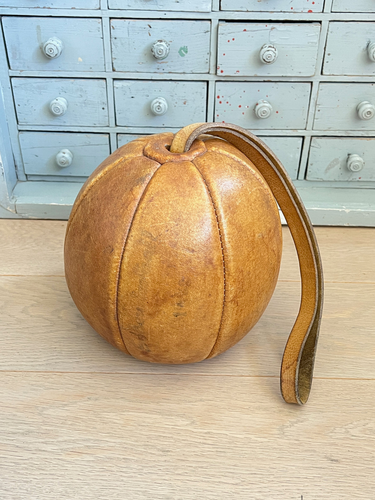 Ancienne balle d'exercice en cuir fauve avec poignée intégrée, objet de sport vintage et de collection avec patine authentique.