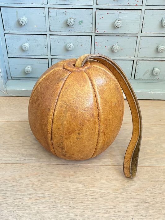 Ancienne balle d'exercice en cuir fauve avec poignée intégrée, objet de sport vintage et de collection avec patine authentique.