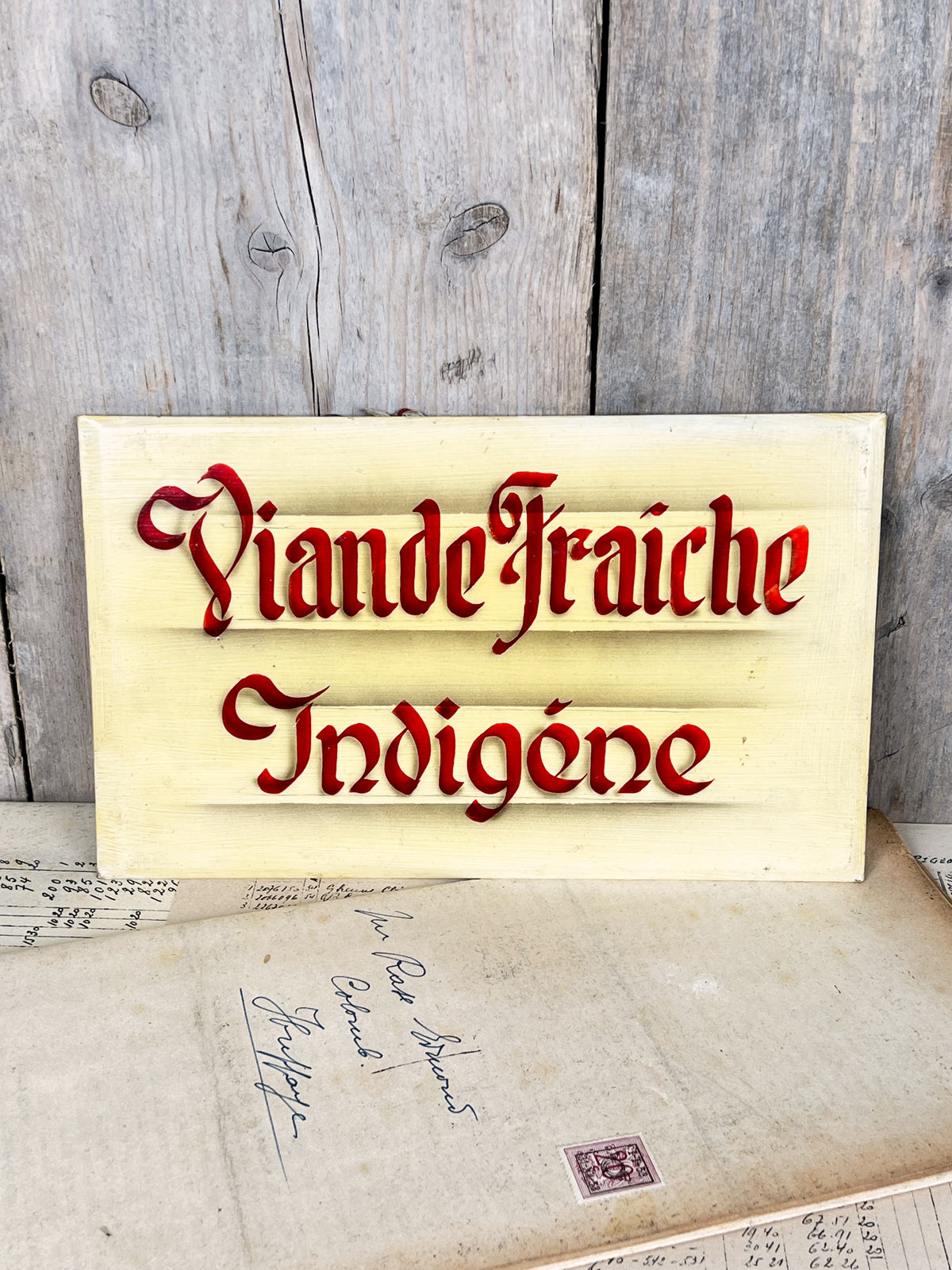 Ancienne enseigne de boucherie en glaçoïde peinte à la main indiquant Viande Fraîche Indigène en lettres gothiques rouges avec ombrages.