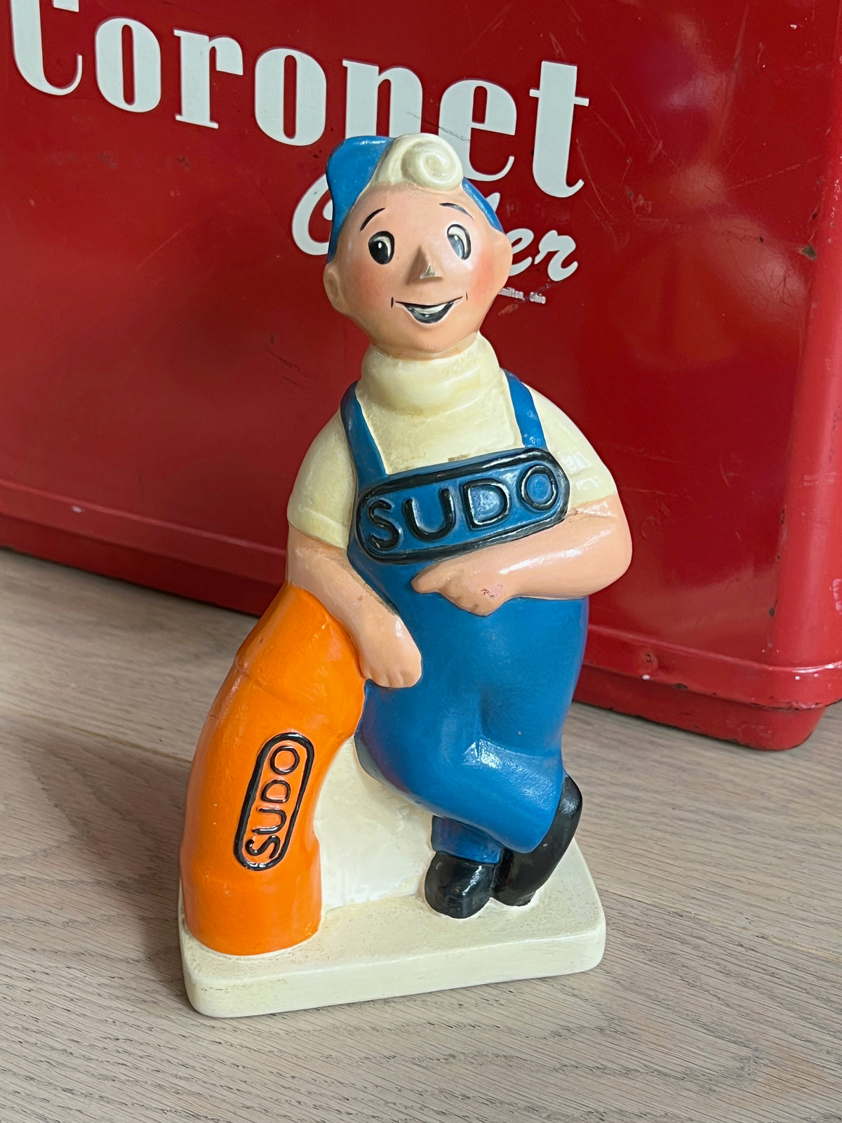 Ancienne tirelire publicitaire en céramique de la mascotte de plomberie Sudo en salopette avec raccord de tuyau, figurine de collection vintage.