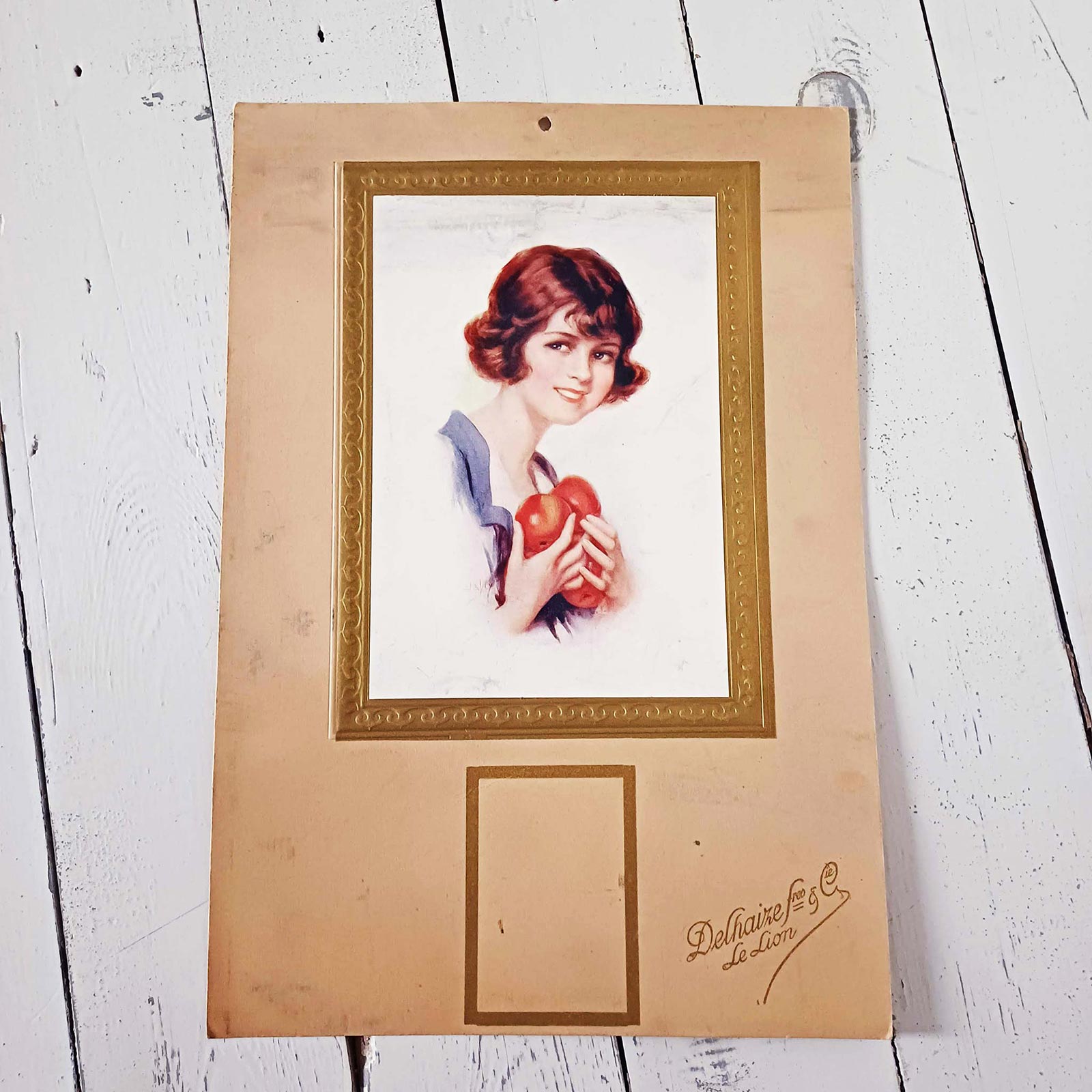 Ancien carton publicitaire Delhaize illustré d’une jeune femme portant des pommes, lithographie vintage Belgique.