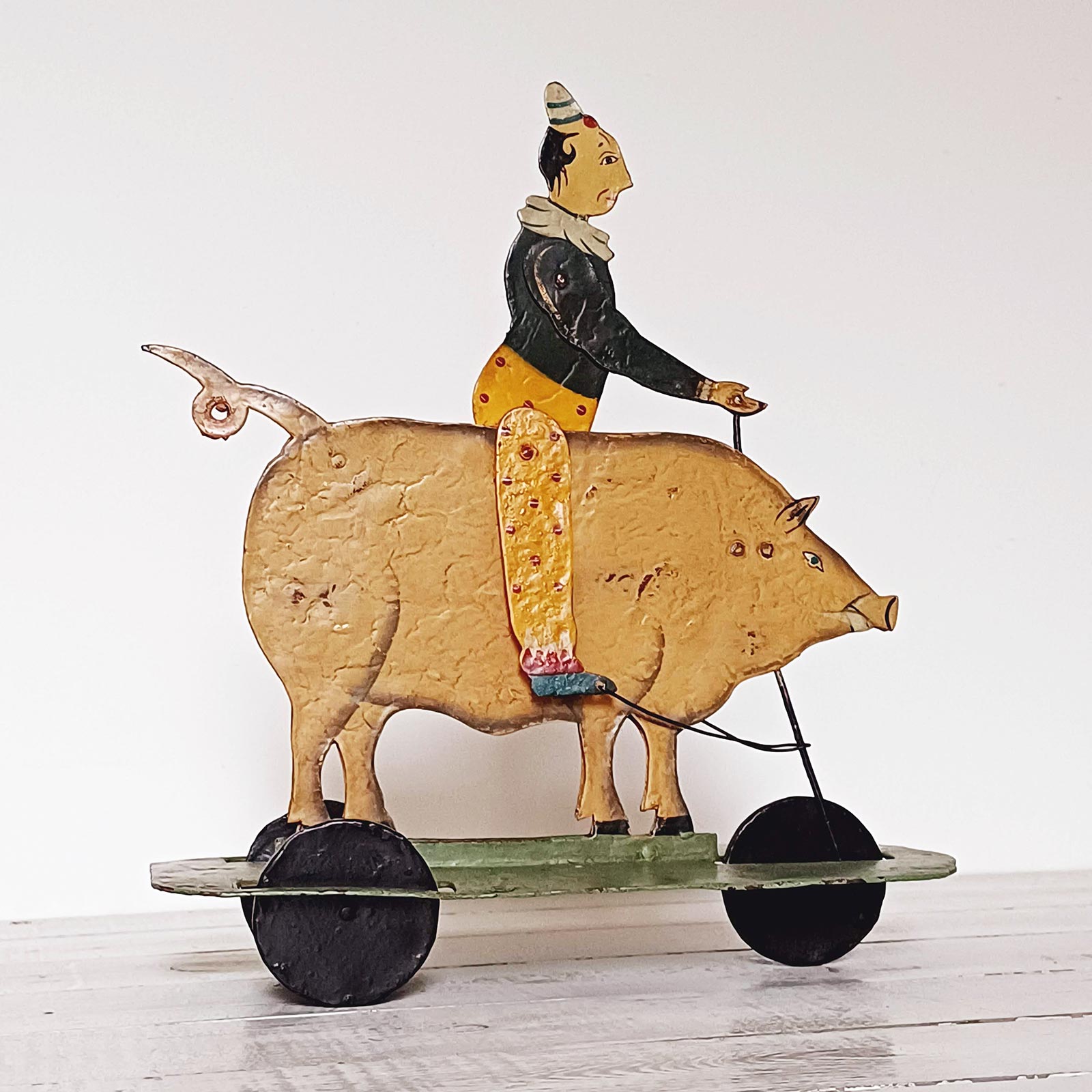 Jouet ancien français en tôle représentant un clown chevauchant un cochon, jouet à tirer peint à la main