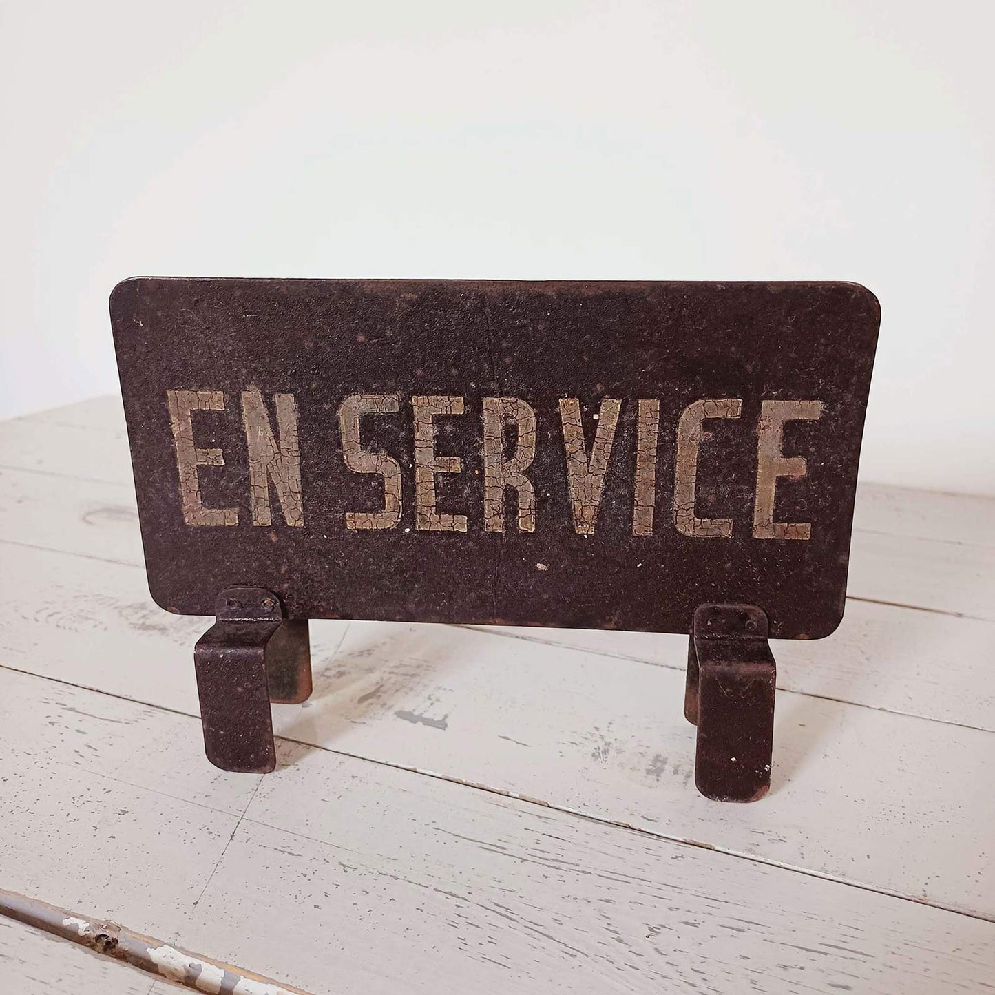 Petit panneau en métal ancien avec l'inscription "En service", tôle peinte à la main, patine foncée, objet vintage de style industriel.