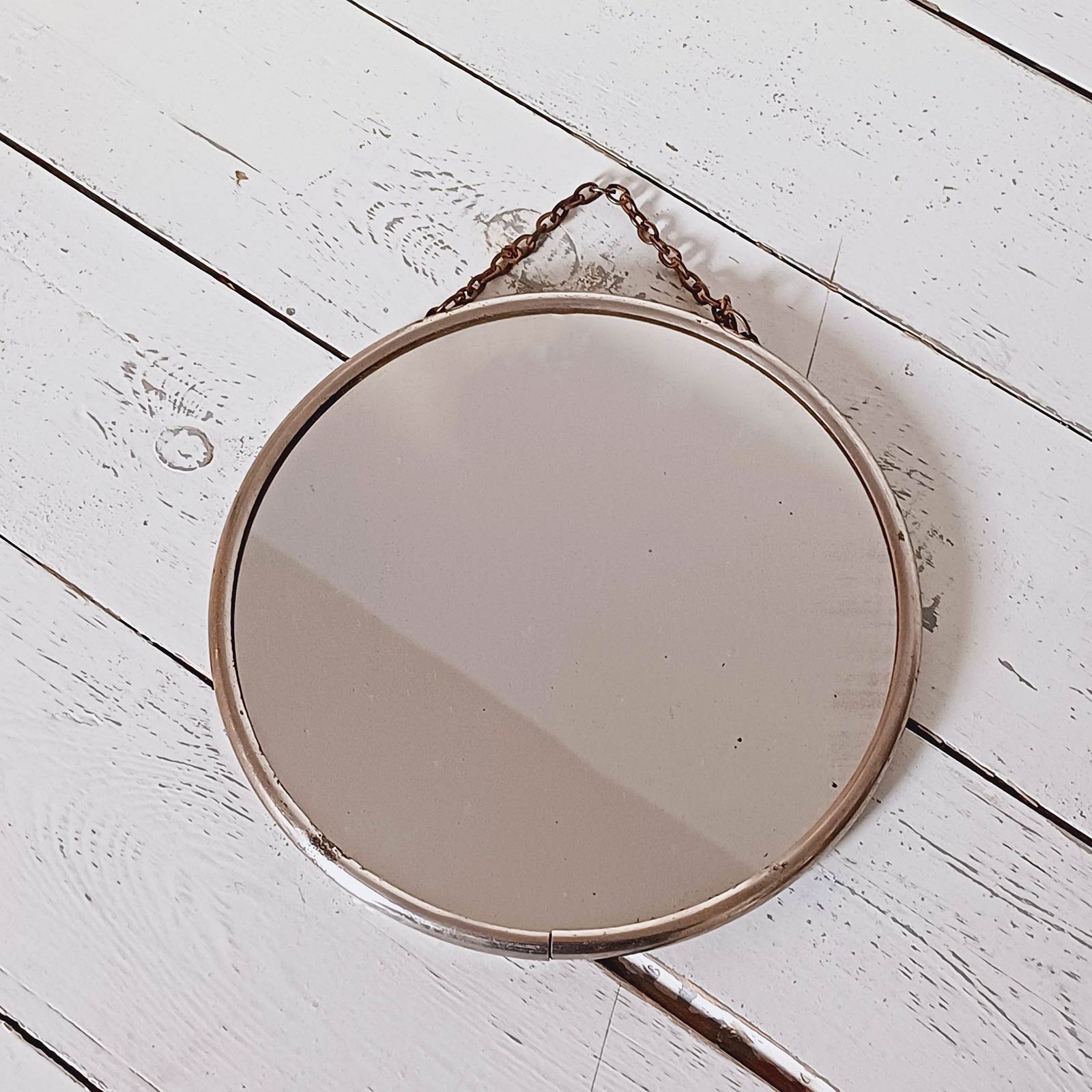 Petit miroir rond vintage de 17 cm à accrocher, cerclage chromé, verre et dos cartonné, en bon état avec légères traces du temps.