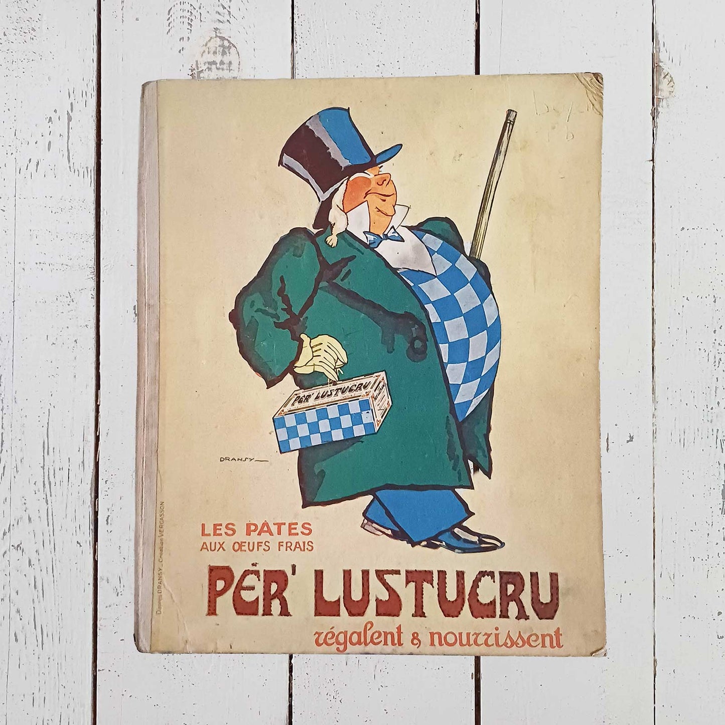 Protège-cahier publicitaire ancien Per' Lustucru en carton épais avec dos toilé, format 23 x 28 cm, illustration de Dransy avec traces du temps.