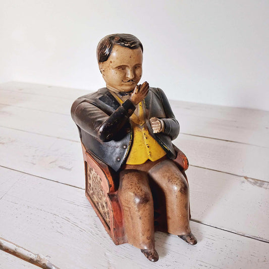 Tirelire mécanique ancienne Tammany Bank en tôle peinte représentant un homme assis, modèle américain breveté en 1873.
