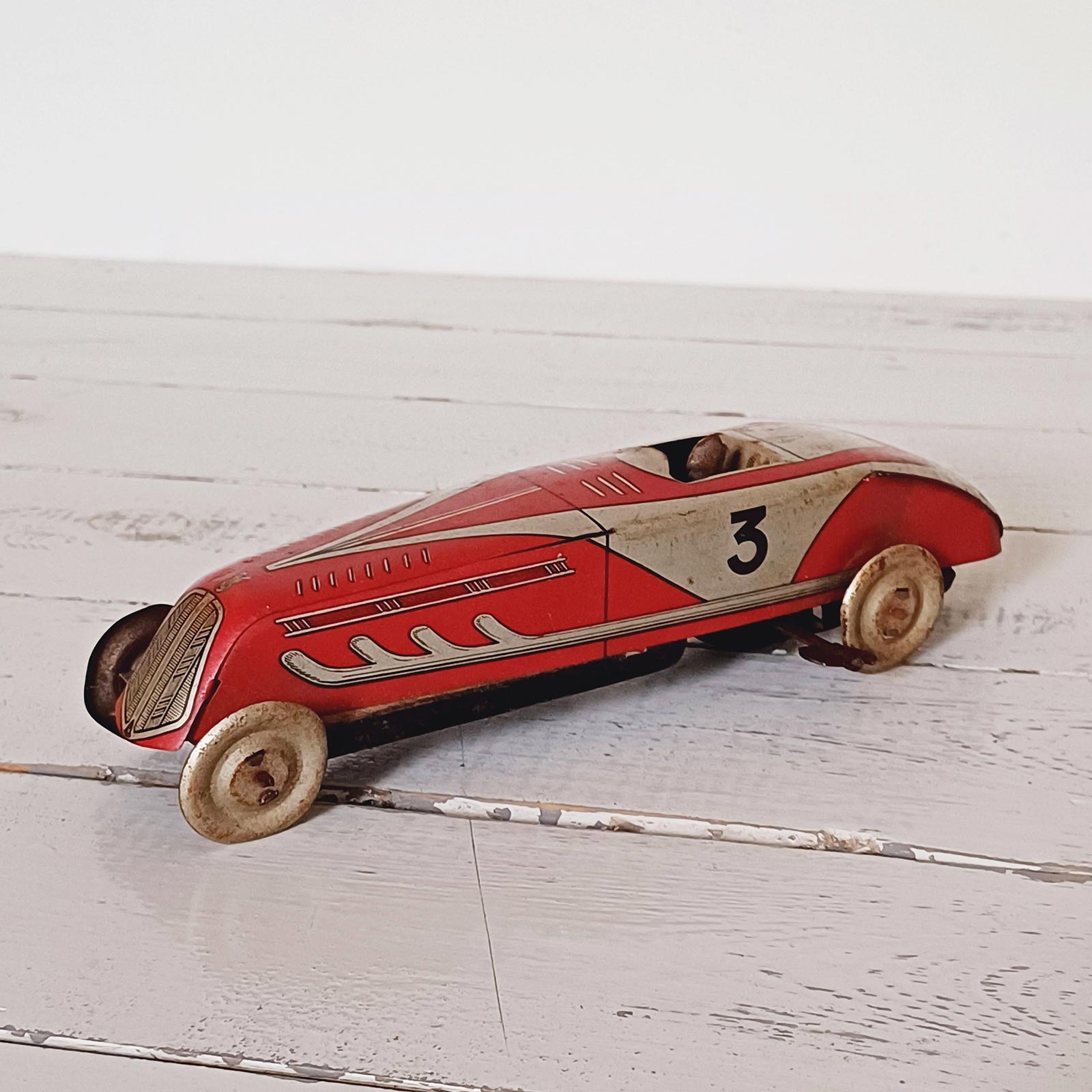 Voiture jouet à remontoir en tôle des années 1930, marque Martinaud & Larnaude, en bon état avec mécanisme fonctionnel.
